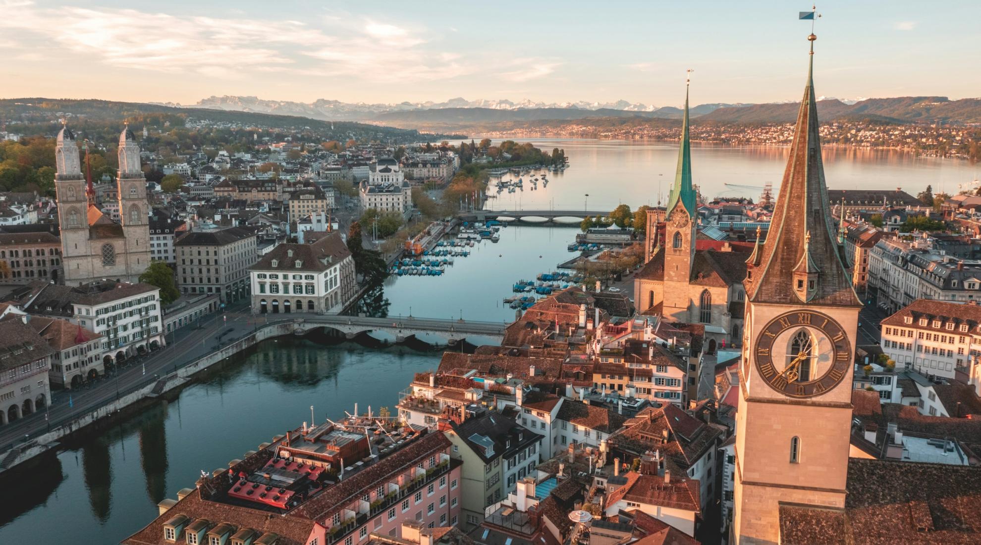 Panoramic aerial view of Zurich’s old town, the Limmat River and Lake Zurich, with the Alps in the background.